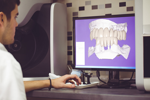 Dental technician using computer to operate dental equipment